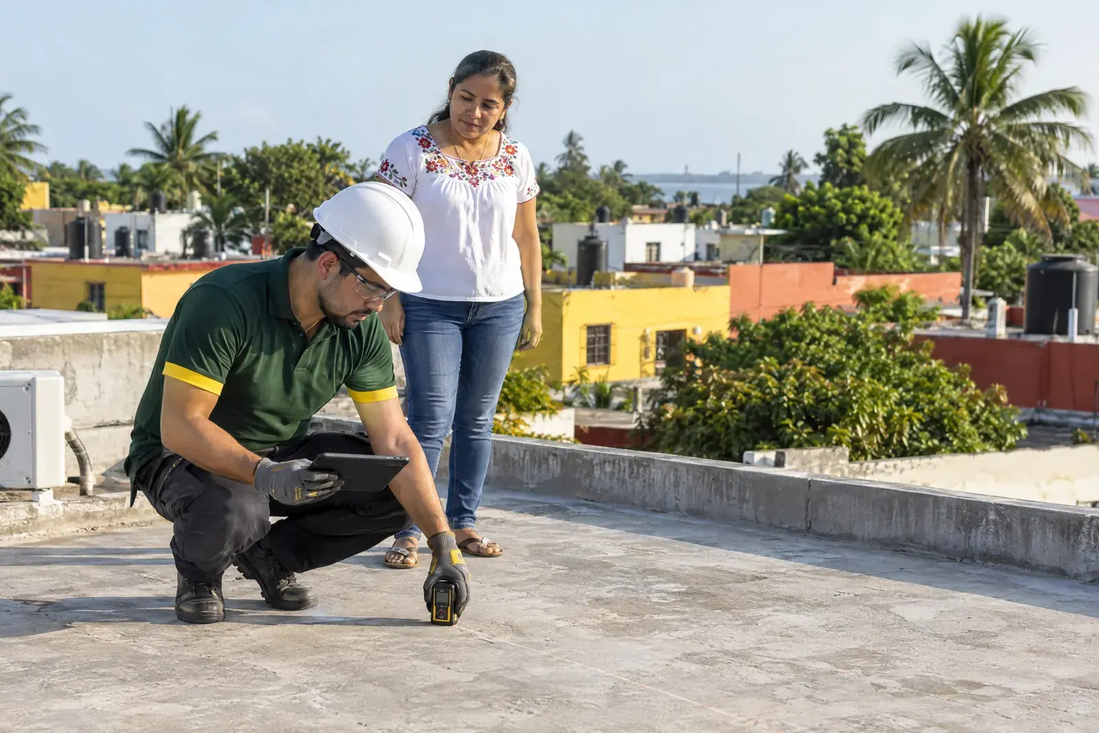 Técnico midiendo una azotea frente a la dueña de la casa